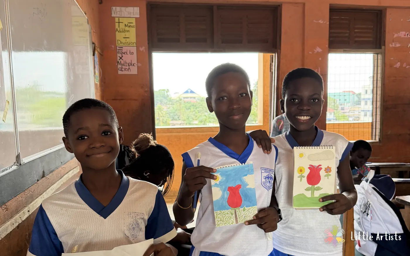 Three students at Achimota Anglican Basic School holding up the drawings they finished