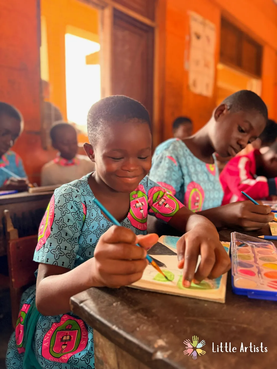 A student at Achimota Anglican Basic School smiling as she paints