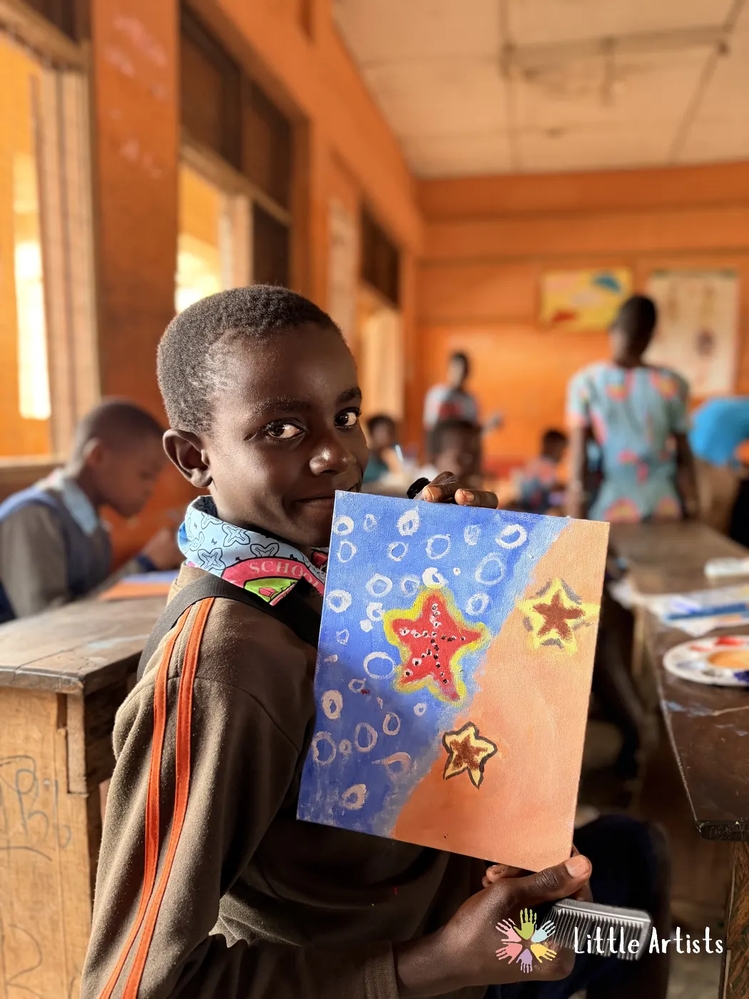 A student holding up his finished starfish painting