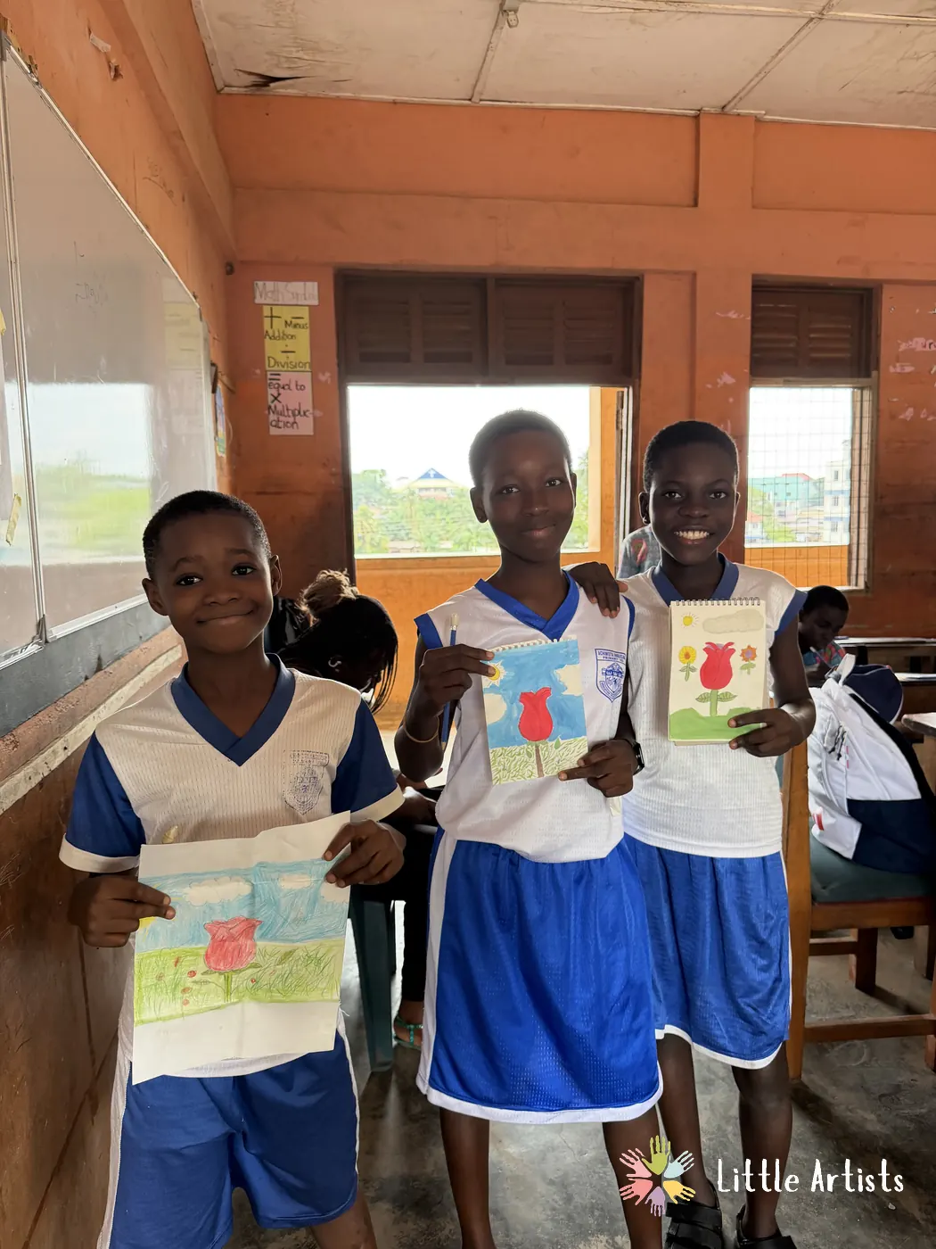 Three students holding up the drawings they finished